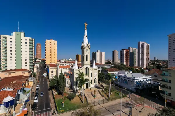 Vista aérea da Igreja Santa Rita e do centro de Uberaba MG, com prédios ao fundo e céu azul"