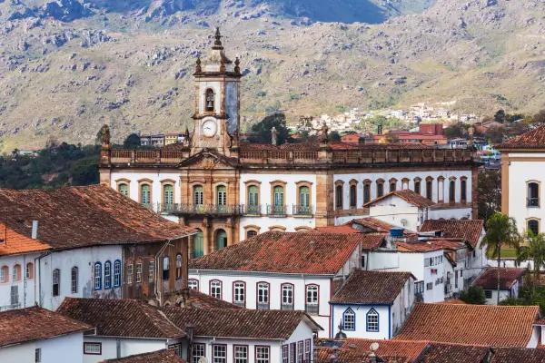 "Vista panorâmica de Ouro Preto, com casarões coloniais, telhados de barro e a torre do Museu da Inconfidência ao fundo, cercados por montanhas históricas de Minas Gerais."