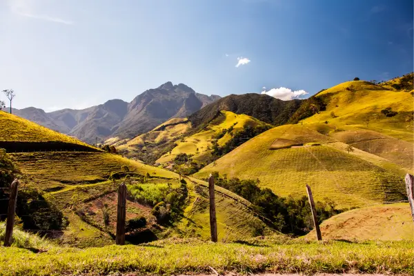 “Montanhas douradas de Aiuruoca na Serra da Mantiqueira, com trilhas e vales iluminados pelo sol — destino ideal para ecoturismo em Minas Gerais.”