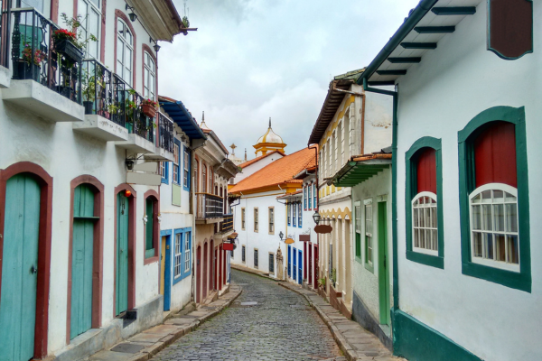 “Rua estreita de paralelepípedos com casarões coloniais coloridos em Minas Gerais, onde muitas pousadas históricas preservam arquitetura e cultura local.”
