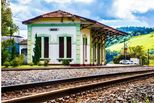 "Antiga estação ferroviária de Minas Gerais com arquitetura histórica preservada ao lado dos trilhos"