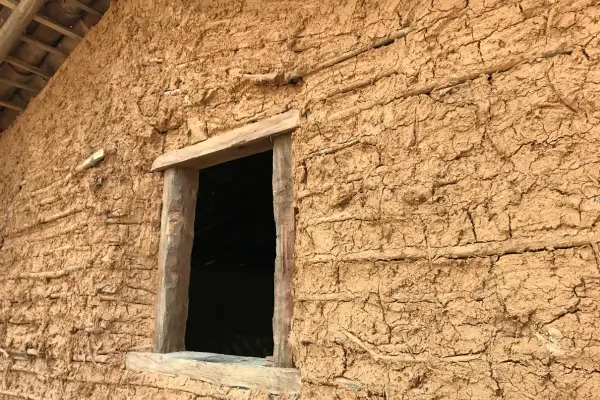 "Parede de casa de taipa com esquadria de madeira, representando a arquitetura sustentável tradicional do interior de Minas Gerais"