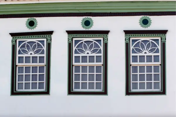 "Janelas coloniais em estilo português com detalhes verdes, representando a influência da arquitetura luso-brasileira no turismo rural de Minas Gerais"