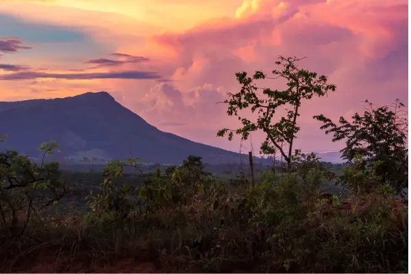 “Pôr do sol colorido na Serra da Canastra com montanhas ao fundo e vegetação típica do cerrado em primeiro plano”