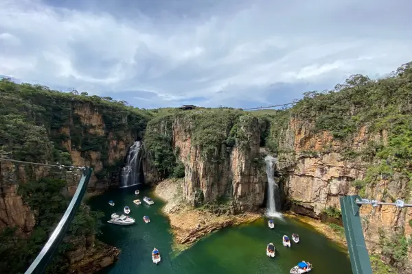 “Canyon de Capitólio com paredões rochosos, lago de águas verdes e barcos navegando entre cachoeiras em Minas Gerais.”