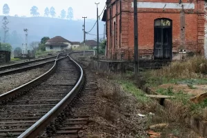 “Antiga estação ferroviária com trilhos curvos e prédio histórico de tijolos, cenário típico de hospedagens ferroviárias transformadas em charme em Minas Gerais.”