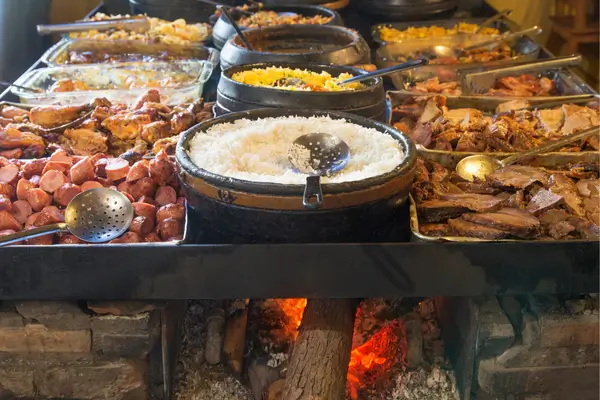 “Fogão a lenha com panelas de comida típica mineira, incluindo arroz, carnes e acompanhamentos regionais”
