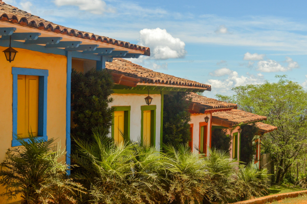 “Fachadas coloniais coloridas de Lavras Novas, MG, em meio à vegetação e clima de serra.”