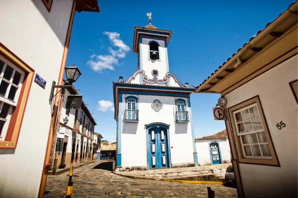 “Igreja histórica de Diamantina, MG, com fachada branca e detalhes azuis, cercada por ruas de pedra no centro colonial da cidade.”