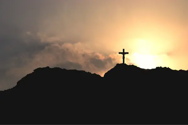 “Cruz no alto de um morro ao pôr do sol, simbolizando fé e espiritualidade no Caminho da Fé em Minas Gerais.”
