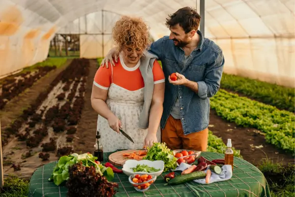 “Produtora colhendo hortaliças frescas em horta local, simbolizando o turismo sustentável e a valorização da agricultura familiar.”