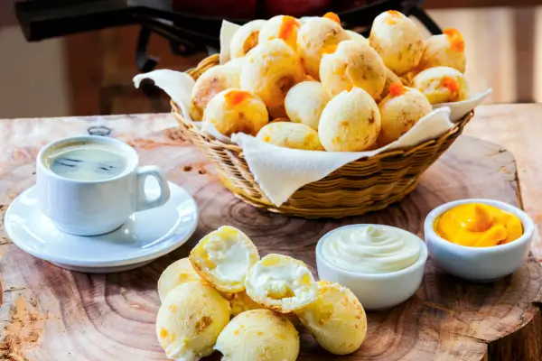 Mesa com pães de queijo, cafés e pates